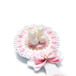 Baby girl shower rattle party favor with baby shoes on decorated table