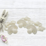 DIY baby shower pacifier decorations set with six white resin pacifiers on wooden background