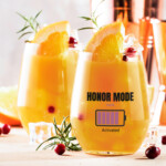 Honor Mode bachelorette party drink glass with battery graphic design mockup on orange cocktail with citrus garnish